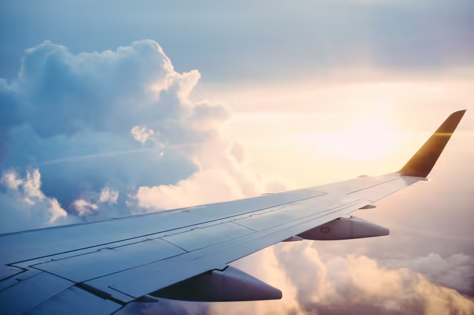Commercial passenger aircraft flying above clouds in clear daylight